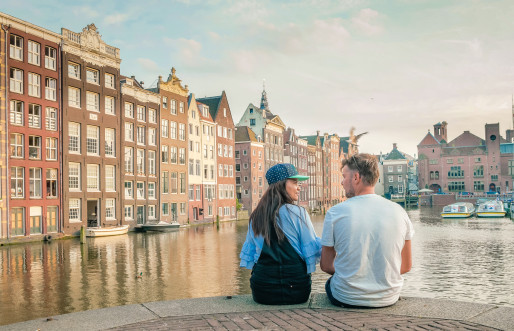 Couple sitting by the side of a canal in Amsterdam city centre