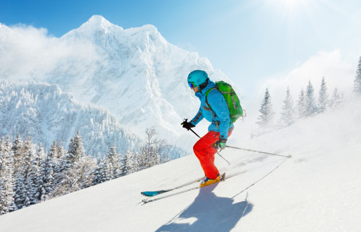 Young male skiíng down snowy slopes